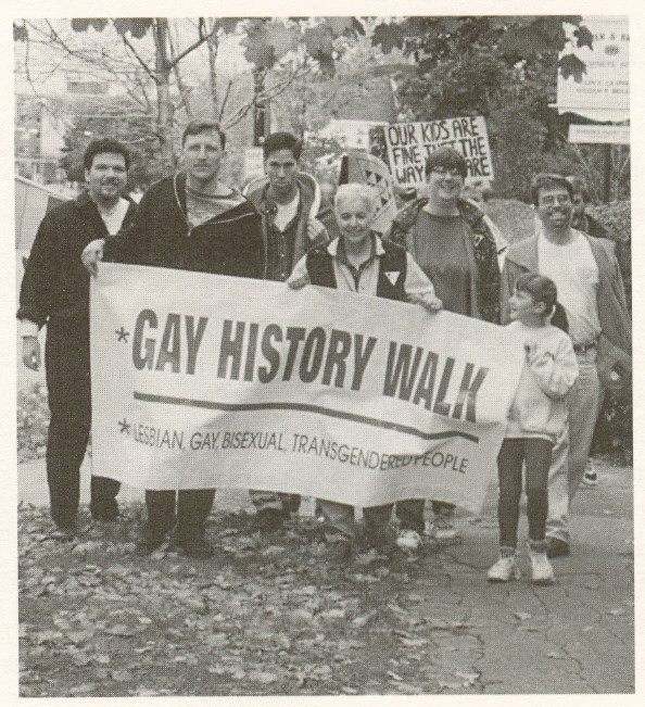 Activists stand with sign saying Gay History Walk