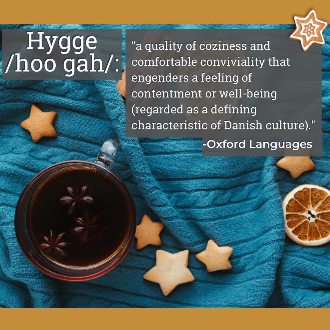 Image of a blue knit sweater laid out with a glass mug of tea and sugar cookies strewn across it. Test reads, "Hygge /Hoo-gah/" and "a quality of coziness and comfortable conviviality that engenders a feeling of contentment or well-being (regarded as a defining characteristic of Danish culture)." 