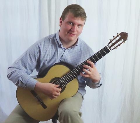 Thatcher Harrison sitting with acoustic guitar