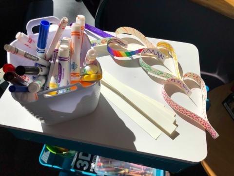 Photo of a pail of markers and a chian of paper hearts